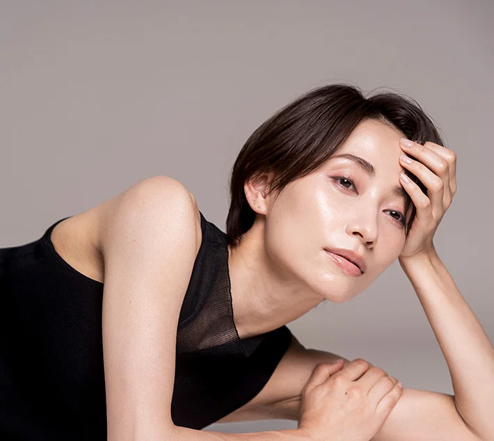 A model with short hair poses gracefully, resting her head on one hand and gazing thoughtfully at the camera. - Brow Lift in West Village, New York, NY