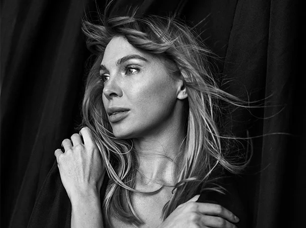A woman with long, tousled hair poses thoughtfully against a dark background, highlighting her serene expression and elegance. - Neck Lift in West Village, New York, NY