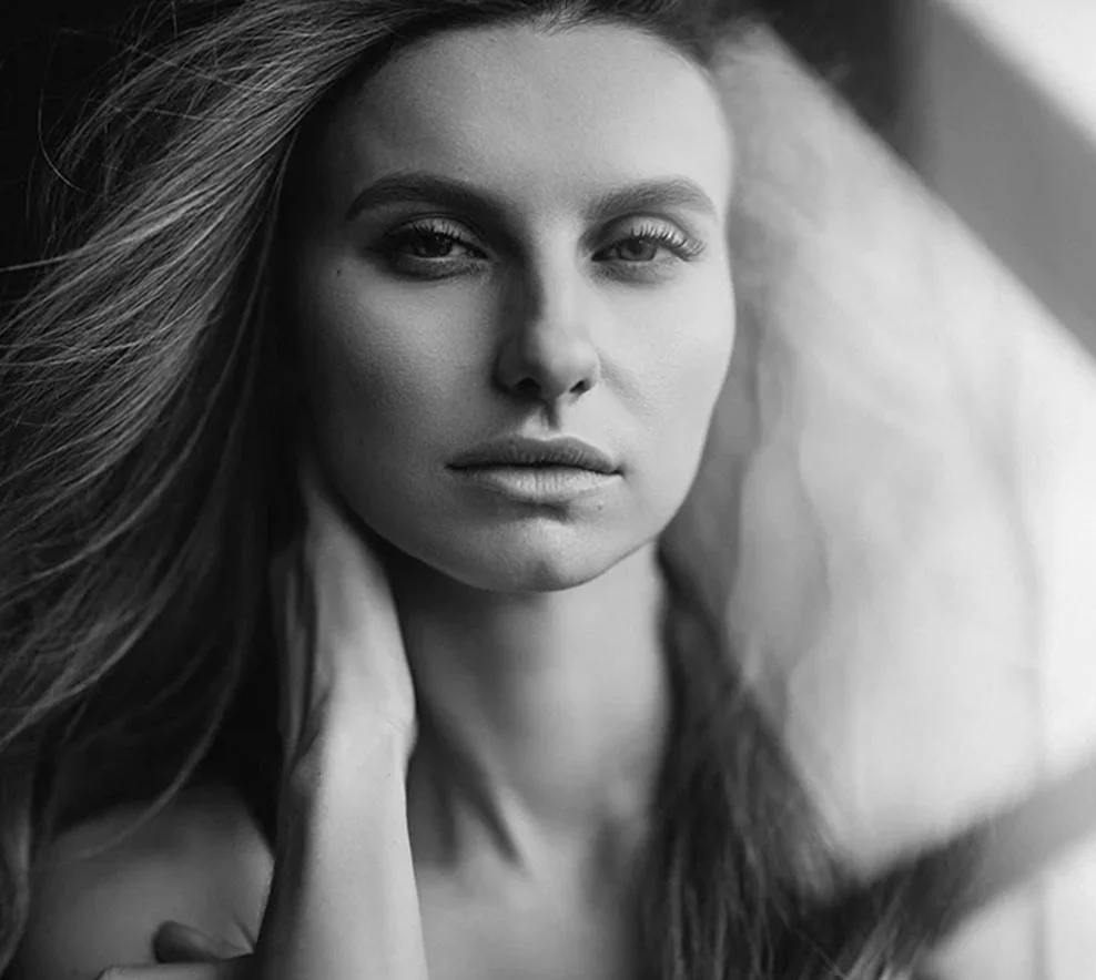 A close-up black-and-white portrait of a woman with long hair, gazing confidently at the camera, softly lit. - Facelift in West Village, New York, NY